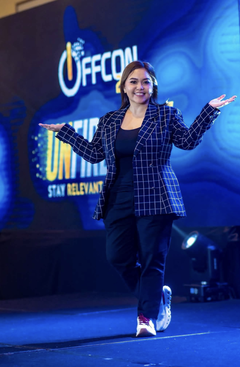 CJ Cajoles on stage at OFFCON, speaking to an audience about staying relevant in the AI era